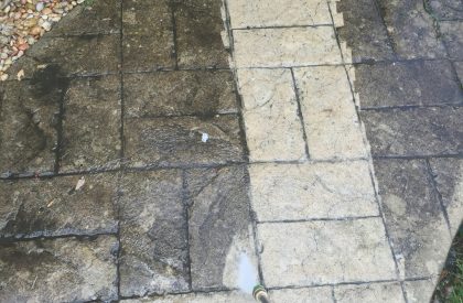 Person power washing the dirt half of a sidewalk making it clean and fresh looking new Person power washing the dirt half of a sidewalk making it clean and fresh looking new